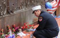 A New York city firefighter pauses at the firefighters memorial wall that displays the names of victims of Sept. 11 at ground zero on the 10th anniversary of the terrorist attacks in New York, Sunday, September 11, 2011. (AP Photo/The Canadian Press, Sean Kilpatrick)