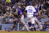Los Angeles Dodgers' Mookie Betts, center, scores on a single by Will Smith as Colorado Rockies catcher Elias Diaz, left, takes a late throw while relief pitcher Jake Bird backs Diaz up during the fourth inning of a baseball game Friday, Sept. 30, 2022, in Los Angeles. (AP Photo/Mark J. Terrill)