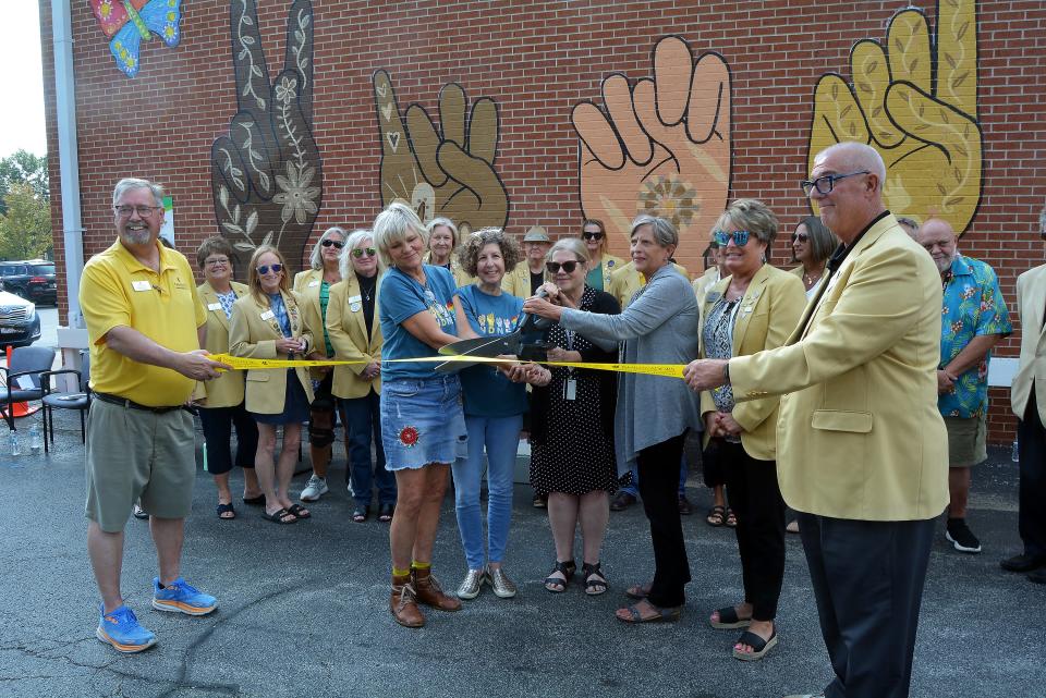 Mural artist Tina Blanck, second from left in front, Children's Grove Art Chair Joyce Smith, Compass Health Regional Vice President Karen Cade and Columbia/Boone County Public Health and Human Services Director Stephanie Browning, while surrounded by Columbia Chamber of Commerce ambassadors, prepare to cut the ribbon Wednesday on the 'Kindness Heals' mural.