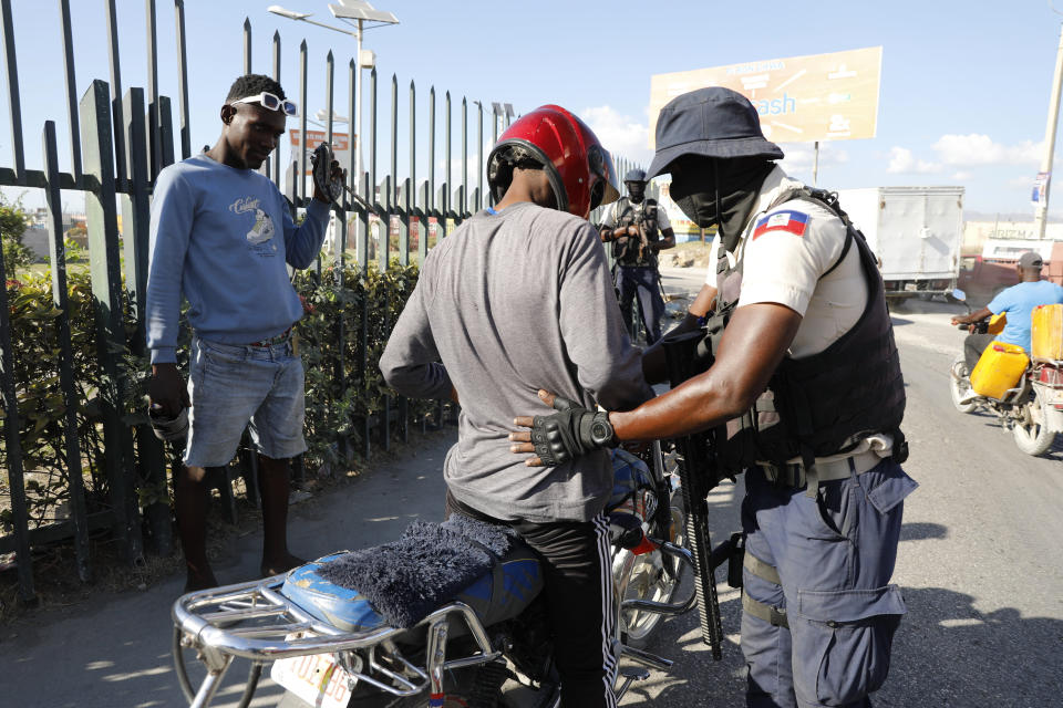 A police officer pats down a motorcyclist at a checkpoint in Port-au-Prince, Haiti, Friday, Jan. 26, 2024. A court in Kenya on Friday blocked the deployment of a U.N.-backed police force to help fight gangs in the troubled Caribbean country. (AP Photo/Odelyn Joseph)