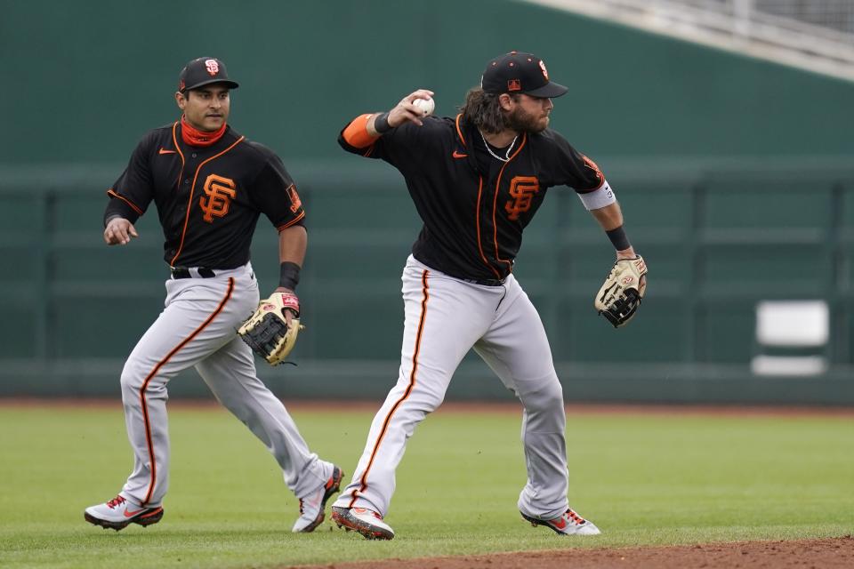 San Francisco Giants shortstop Brandon Crawford, right, fields a grounder hit by Cleveland Indians' Ben Gamel as Giants second baseman Donovan Solano, left, backs up the play during the third inning of a spring training baseball game Tuesday, March 23, 2021, in Goodyear, Ariz. Giants' Crawford had a throwing error on the play and Indians' Gamel reached first base safely. (AP Photo/Ross D. Franklin)