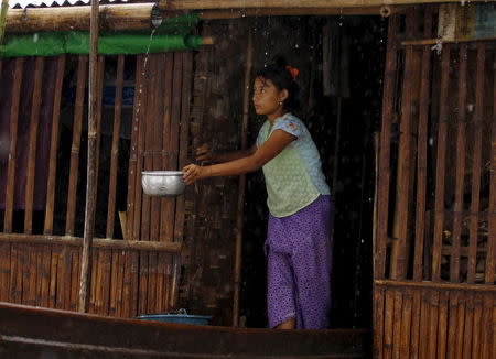 A woman collects rain water at her home in a flooded village outside Zalun Township, Irrawaddy Delta, Myanmar, August 6, 2015. REUTERS/Soe Zeya Tun