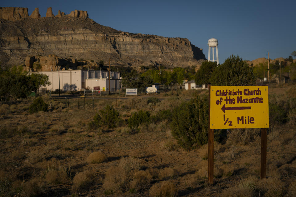 A hand-painted sign points the way to the Chilchinbeto Church of the Nazarene in Chilchinbeto, Ariz., on the Navajo reservation at sunrise on Sunday, April 19, 2020. The Navajo reservation has some of the highest rates of coronavirus in the country. If Navajos are susceptible to the virus' spread in part because they are so closely knit, that's also how many believe they will beat it. (AP Photo/Carolyn Kaster)