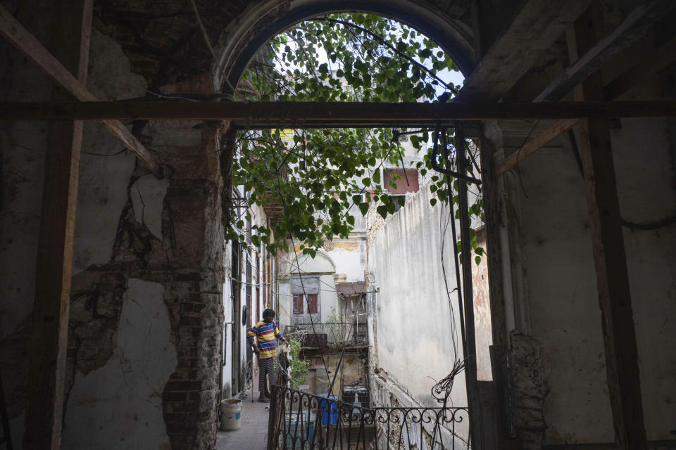 Regla Victoria Rodriguez stands on the balcony of her dilapidated home on Villegas Street in Havana, Cuba, Wednesday, Oct. 18, 2023. The two-story building, which houses six families, is one of many, once luxurious houses that in recent years have partially collapsed or suffered visible damage. (AP Photo/Ramon Espinosa)