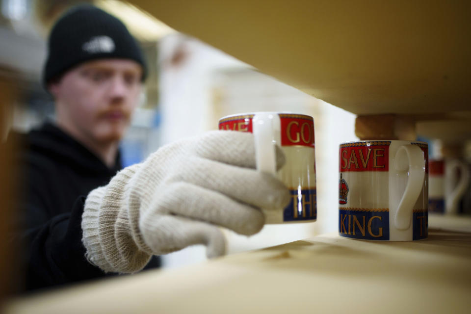 Kiln placer Nathan Davies prepares mugs for firing, at the Duchess China 1888 factory, in Stoke-on-Trent, England, Thursday, March 30, 2023. With just five weeks to go until King Charles III’s coronation, an historic pottery is busy producing “God Save The King” commemorative china plates and mugs to mark the occasion. (AP Photo/Jon Super)