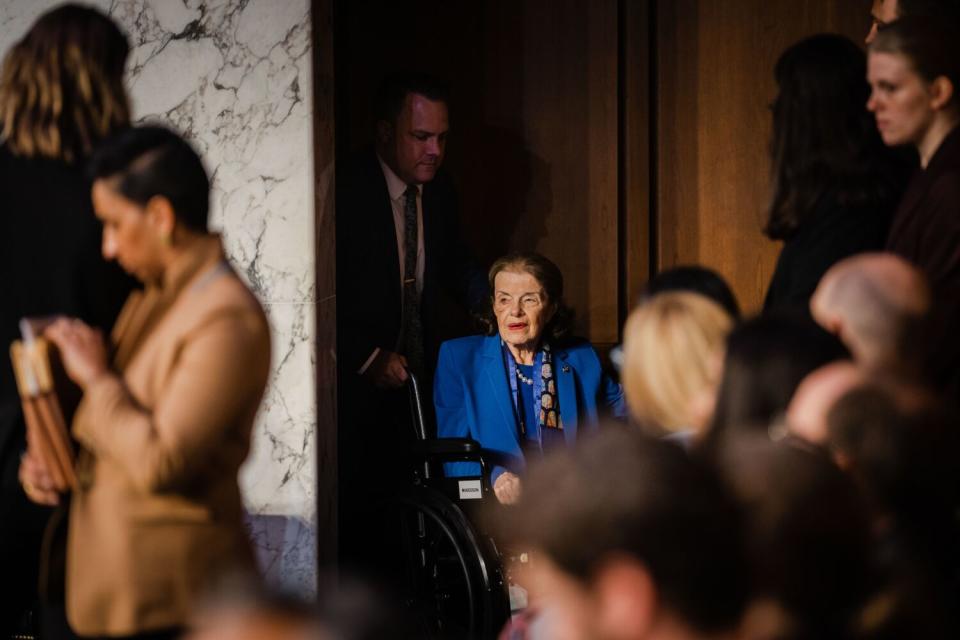 A person pushes another person in a wheelchair into a room.