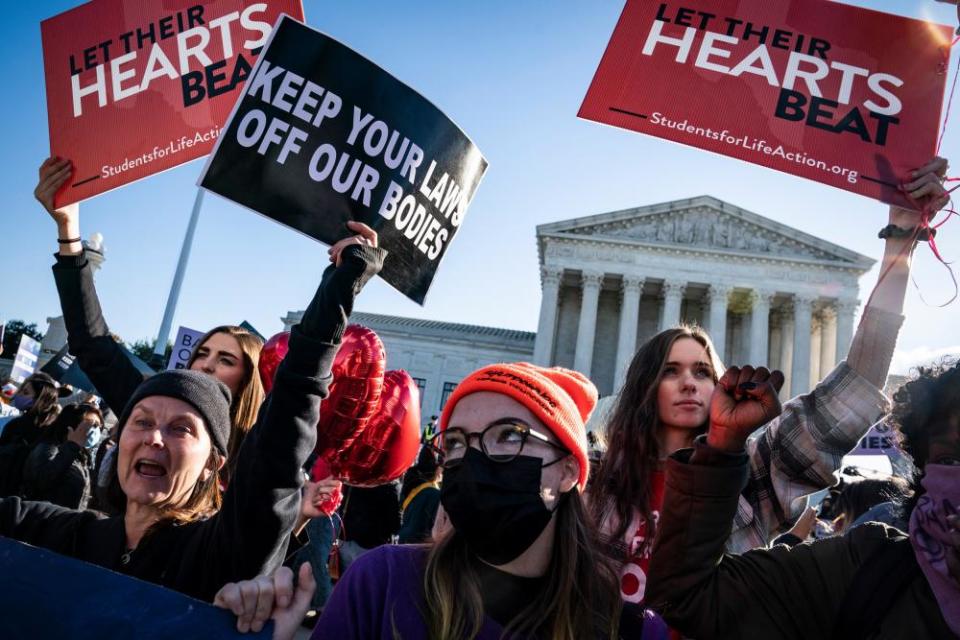 People hold signs saying 'keep your laws off our bodies' and 'let their hearts beat'