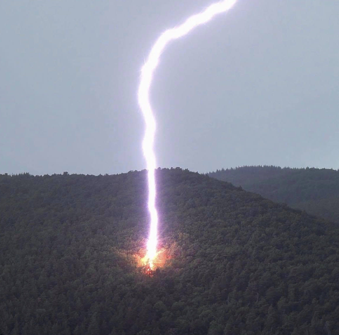 This incredible image captures a gigantic lightning bolt as it strikes the side of a mountain in Pecos, New Mexico. (SWNS)