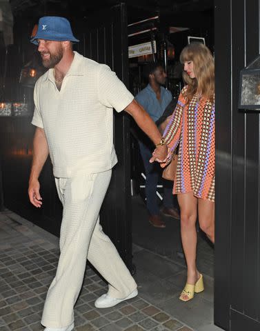 <p>CH/SplashNews</p> Travis Kelce (left) holds Taylor Swift's hand in London