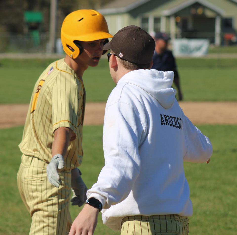 Pellston's Brett Bonter (left) gets congratulated by coach Jared Anderson after reaching third base during game one against Onaway on Friday.