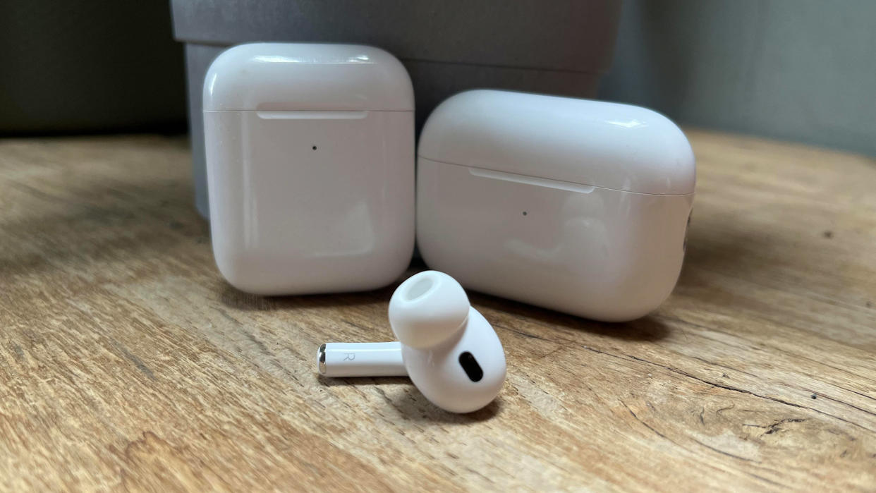  A single AirPod in front of two cases. 