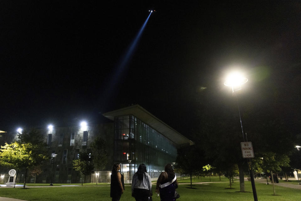 Students watch as a police helicopter flies over Morgan State University after a shooting, Wednesday, Oct. 4, 2023, in Baltimore. (AP Photo/Julia Nikhinson)