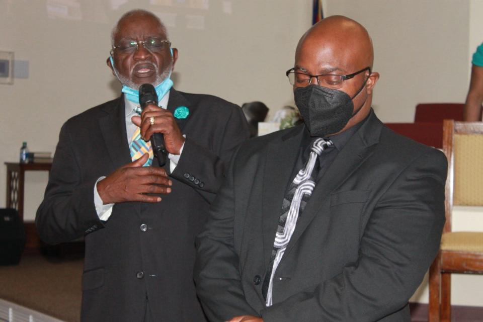 Deacons Kenneth Simmons, left, and Billy Daniels, right, of First Missionary Baptist Church led the invocation prayer during a pastor's anniversary celebration service at the church on Sunday.