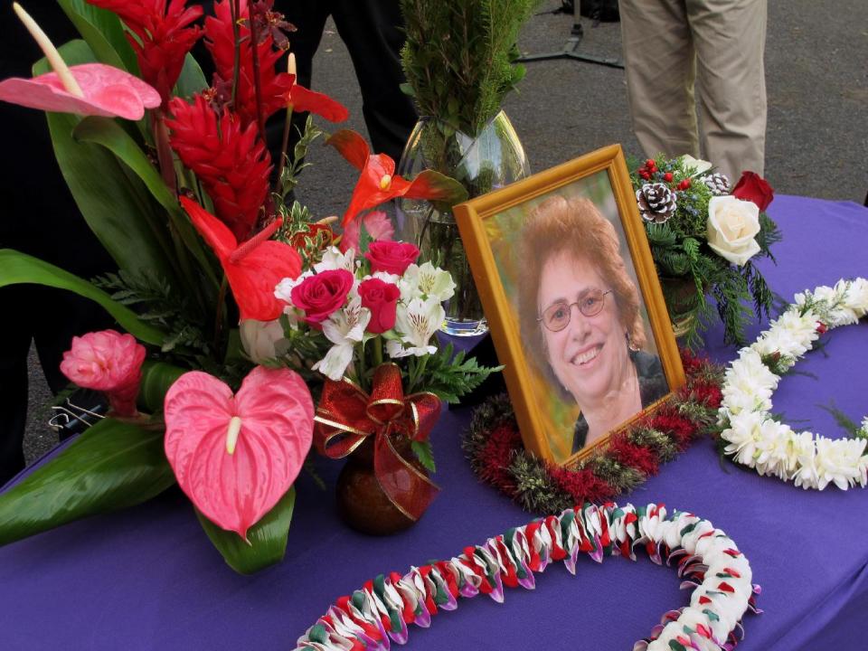 FILE - In this Dec. 12, 2013 file photo, a memorial for Loretta Fuddy, the director of the state Department of Health, is displayed outside the department in Honolulu. Fudday was killed after a small plane with nine people aboard crashed into the water off the Hawaiian island of Molokai Wednesday Dec. 11, 2013 according to Tom Matsuda, the interim executive director of Hawaii's health insurance exchange. Fuddy was 65. Police say the cause of death for the Hawaii health director who died after a plane’s crash-landing off the Hawaiian island of Molokai was cardiac arrhythmia. Maui police announced Monday Jan. 13, 2014, that Loretta Fuddy’s condition was the result of stress from the Dec. 11 crash into the water after the single-engine plane lost power. The pilot and eight other passengers survived without major injuries. (AP Photo/Audrey McAvoy, File)