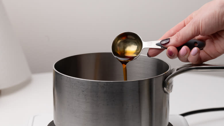 hand pouring maple syrup into a pan