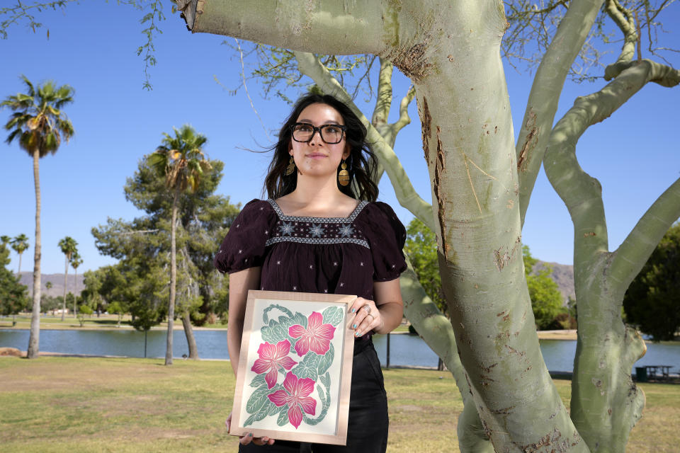Olivia Yuen, 29, a middle school art teacher and well-known artist in Phoenix, who has a Chinese father and a Mexican mother, holds one of her linocut block prints Tuesday, May 21, 2024, in Laveen, Ariz. (AP Photo/Ross D. Franklin)