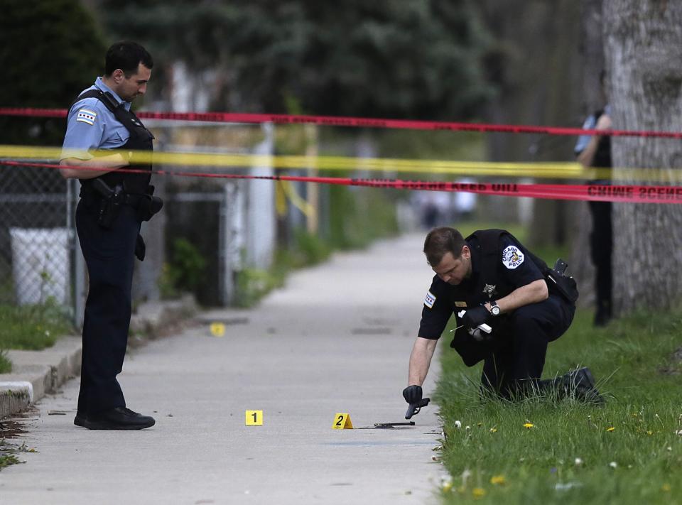 A Chicago Police officer, left, watches as an evidence technician officer investigates a gun at the scene where a 16-year-old boy was shot in the head and killed and another 18-year-old man was shot and wounded on the 7300 block of South Sangamon Street on April 25, 2016 in Chicago, Illinois. (Photo: Joshua Lott/Getty Images)