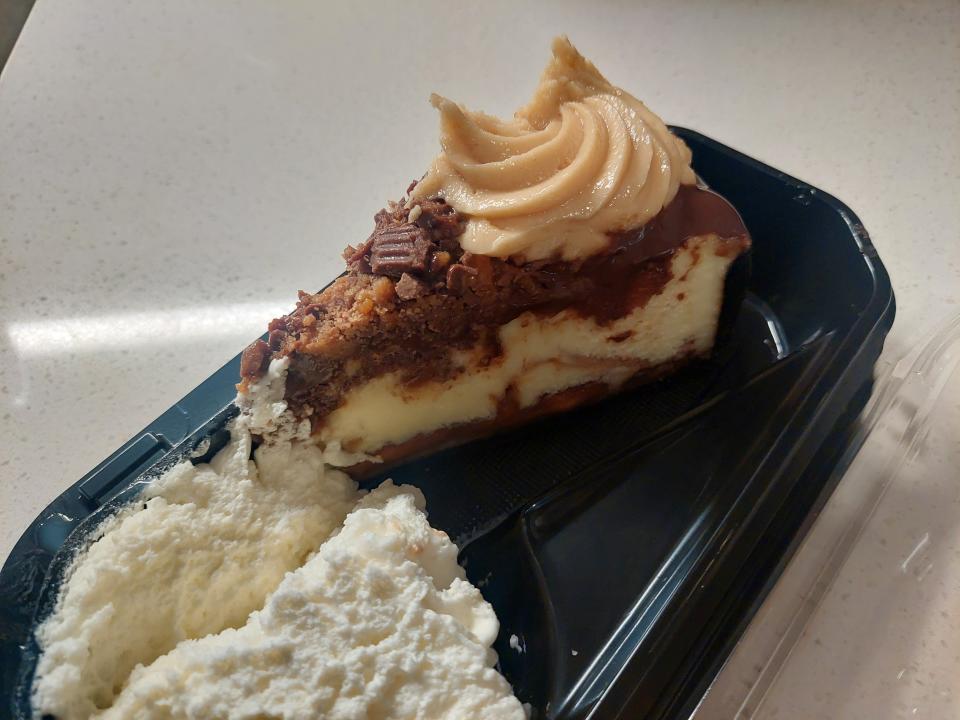 A photo of a slice of the Adam's Peanut Butter Cup Fudge Ripple Cheesecake in a tray at the Cheesecake Factory