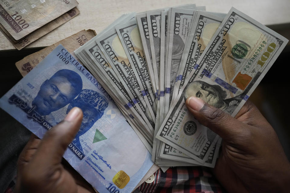 A man display U.S. $100 bills alongside Nigerian currency at the craft and art market in Lagos, Nigeria, on Wednesday, Aug. 16, 2023. Across the developing world, many countries are fed up with America's dominance of the global financial system — and especially the power of the dollar. (AP Photo/Sunday Alamba)