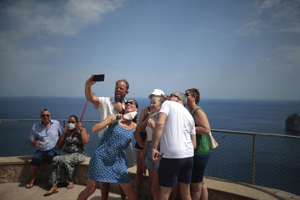 Tourists visiting from the UK take a selfie at a viewpoint in Pollença, in the Balearic Island of Mallorca, Spain, Tuesday, July 28, 2020. Britain has put Spain back on its unsafe list and announced Saturday that travelers arriving in the U.K. from Spain must now quarantine for 14 days. (AP Photo/Joan Mateu)