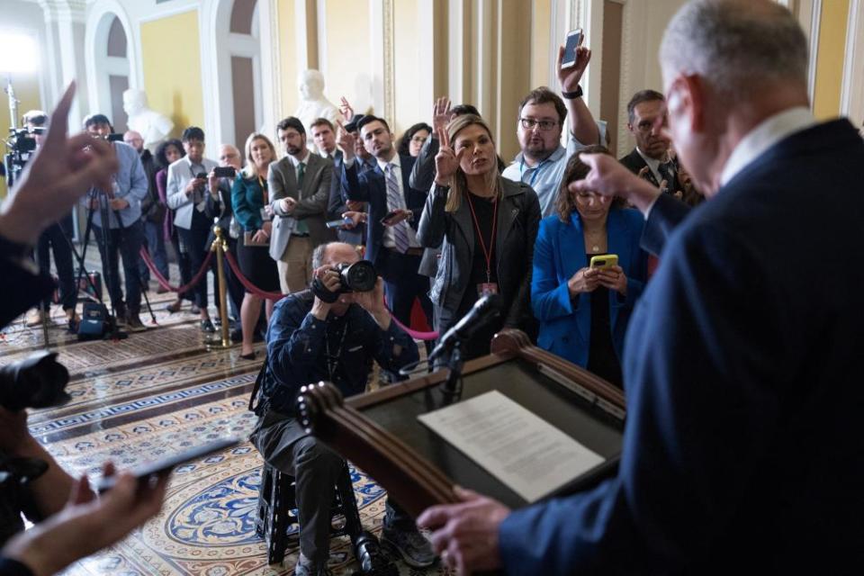 schumer viewed from the back with crowd of reporters around him