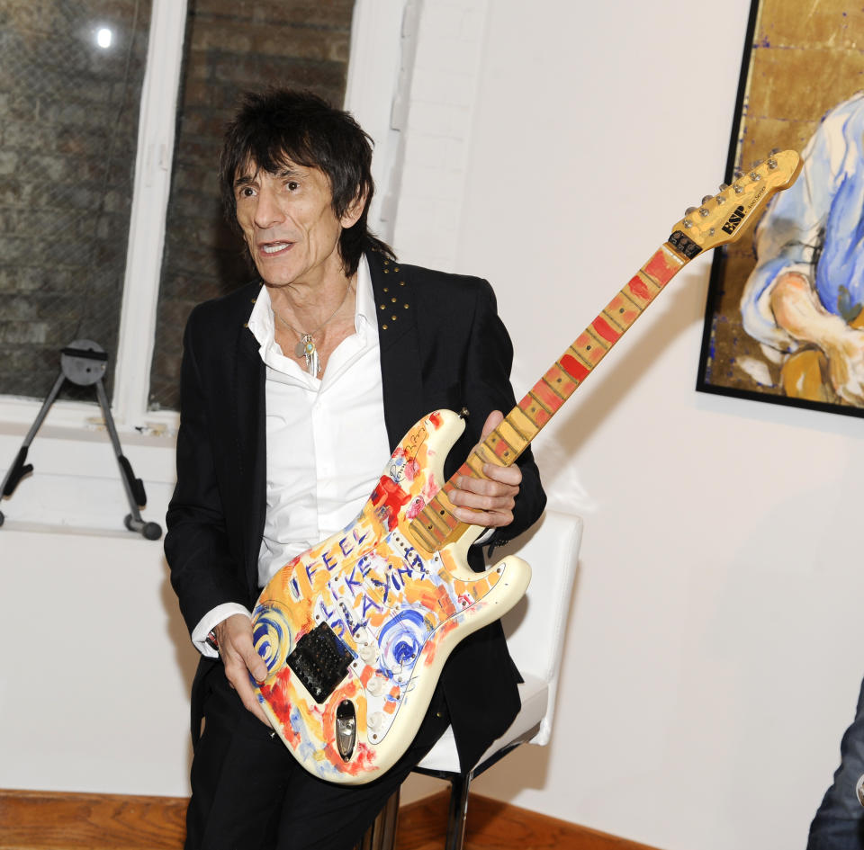 Rolling Stones guitarist Ronnie Wood holds up one of his works of art during a news conference unveiling his new art exhibit "Faces, Time and Places" on Monday, April 9, 2012, in New York. (AP Photo/Evan Agostini)