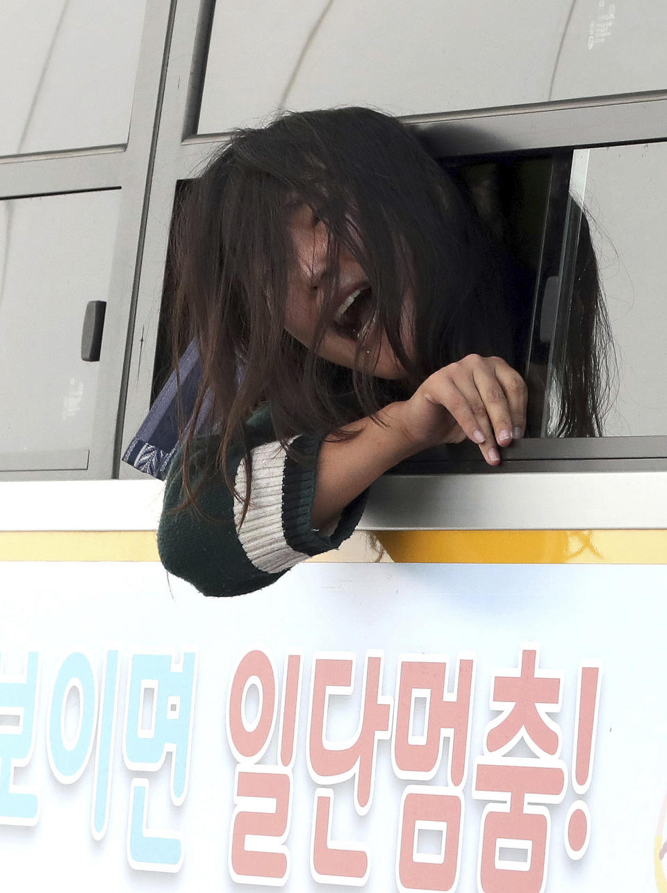 In this Friday, Oct. 18, 2019, photo, a detained college student shouts a slogan into a police bus in front of the U.S. ambassador's residence in Seoul, South Korea. South Korean police said Saturday, Oct. 19, they beefed up security at the U.S. ambassador's residence in Seoul after a group of anti-American students used ladders to break into the compound. The sign reads "Stop" (Chun Jin-hwan/Newsis via AP)