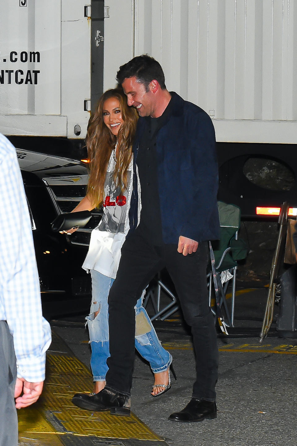 Lopez and Affleck are smiling as they walk through a backstage area