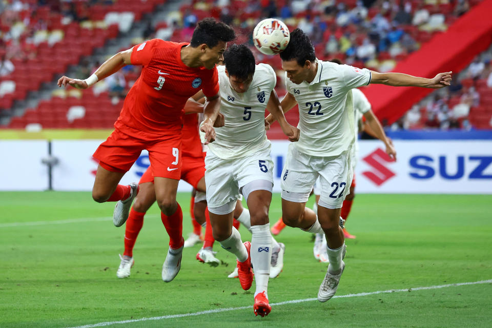 Singapore striker Ikhsan Fandi (left) heads the ball off a corner kick against Thailand's Yusef Elias Dolah (centre) and Supachai Chaided during theirr AFF Suzuki Cup Group A match. 