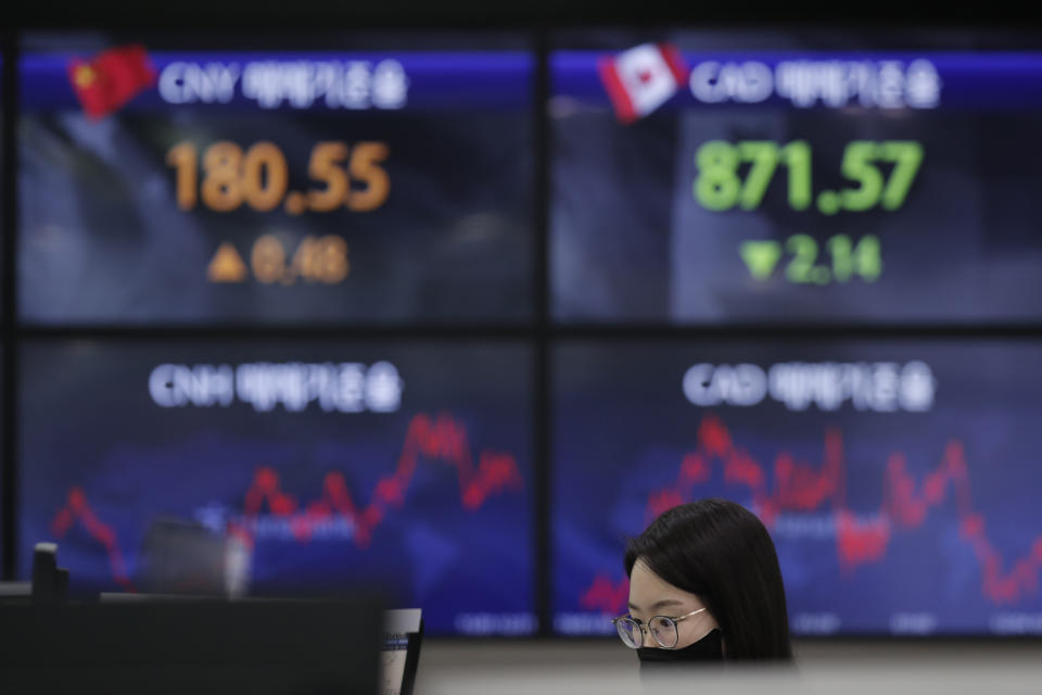 An employee of a bank watches computer monitors near screens showing the foreign exchange rates at the foreign exchange dealing room in Seoul, South Korea, Thursday, Feb. 4, 2021. Asian shares mostly fell Thursday as caution set in over company earnings reports, recent choppy trading in technology stocks and prospects for more economic stimulus for a world battling a pandemic. (AP Photo/Lee Jin-man)