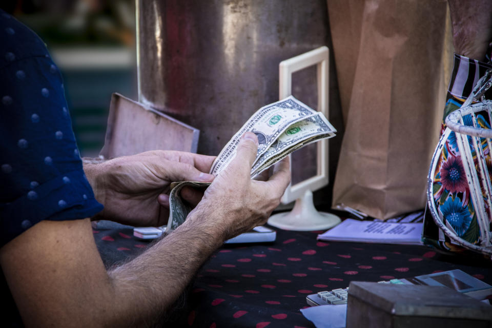 Man counting dollars at a checkout station