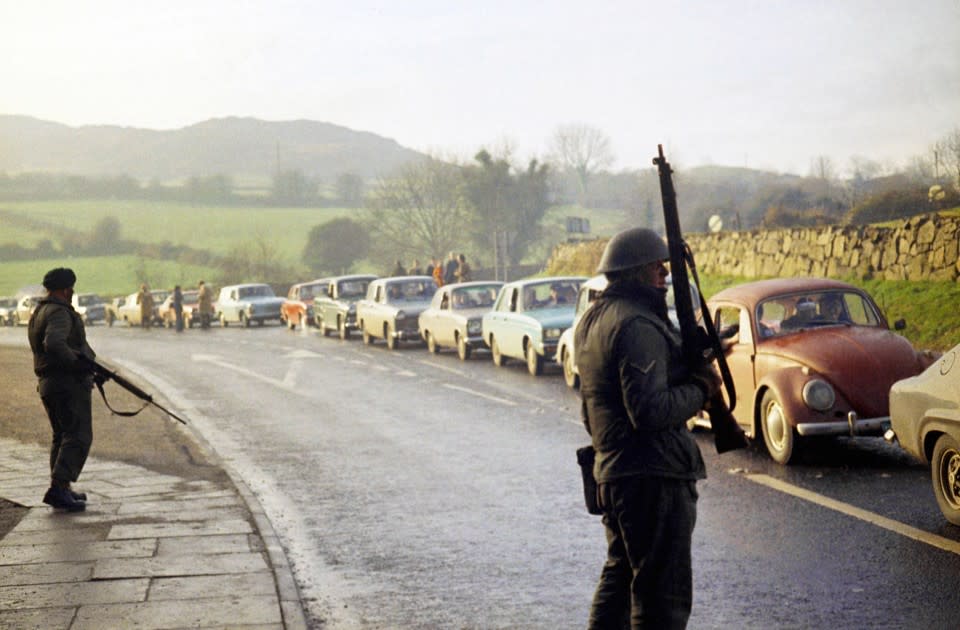 British troops stand guard on a road on the outskirts of the Northern Ireland border town of Newry on Feb. 6, 1972. (AP)