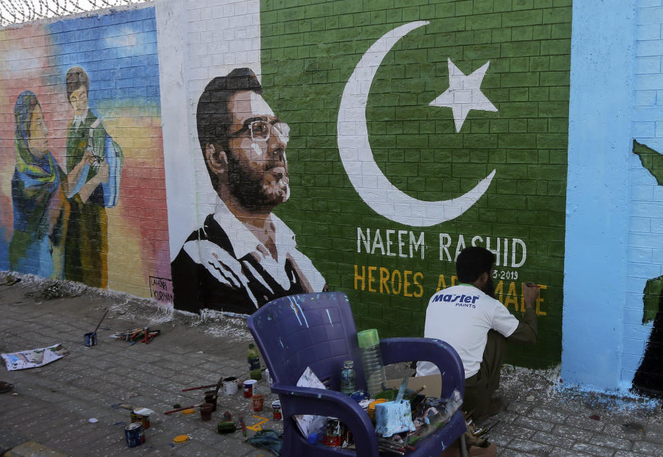 A student gives finishing touches to a mural paying tribute to Naeem Rashid, center, a Pakistani citizen who was killed in the Christchurch mosque shootings, at a school in Lahore, Pakistan, Sunday, March 24, 2019. Rashid along with his son and 48 others were killed in a terror attack at two mosques in New Zealand, on March 15. (AP Photo/K.M. Chaudary)