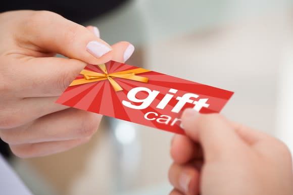 One person handing a gift card to another.