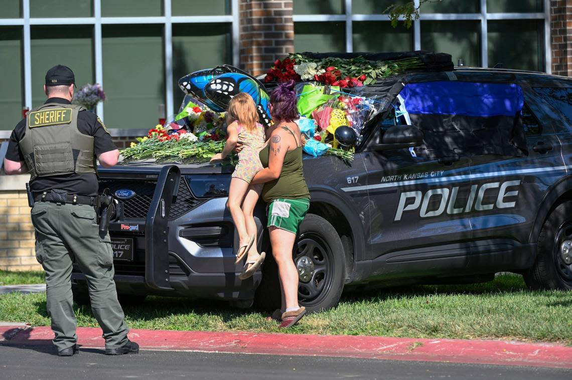 Clay County Sheriff Deputy Kevin Scheib, left, looked on and paid tribute to fallen North Kansas City Police officer Daniel Vasquez, who died in the line of duty Tuesday after being fatally shot in North Kansas City. Shannon Ashcroft, right, hoisted her daughter, Kota-Jo., 7, so she could leave flowers on officer’s police vehicle outside North Kansas City Police Department on Wednesday, July 20, 2022. “He was a friend to everyone,” said Scheib, who worked with Vasquez for about five years at a security company. “He’d give the shirt off his back to anyone.”