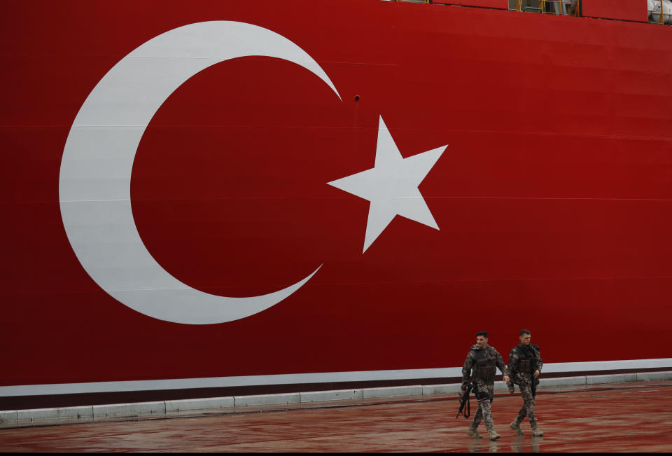 Turkish police officers patrol the dock, backdropped by the drilling ship 'Yavuz' scheduled to be dispatched to the Mediterranean, at the port of Dilovasi, outside Istanbul, Thursday, June 20, 2019. Turkish officials say the drillship Yavuz will be dispatched to an area off Cyprus to drill for gas. Another drillship, the Fatih, is now drilling off Cyprus' west coast at a distance of approximately 40 miles in waters where the east Mediterranean island nation has exclusive economic rights. The Cyprus government says Turkey's actions contravene international law and violate Cypriot sovereign rights. (AP Photo/Lefteris Pitarakis)