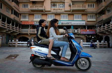 FILE PHOTO: Girls ride an electric scooter in Ahmedabad