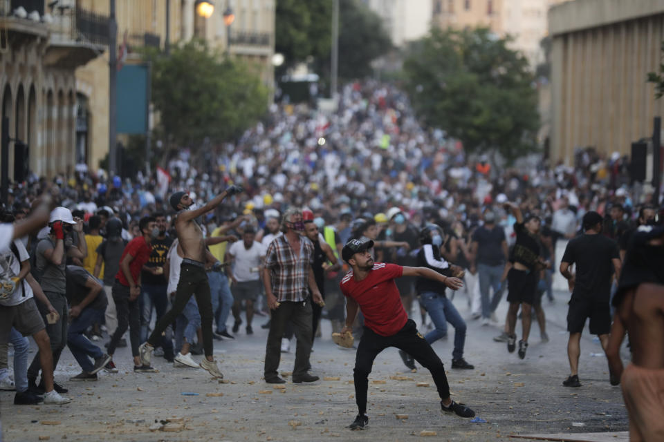 People throw stones during anti-government protest following Tuesday's massive explosion which devastated Beirut, Lebanon, Sunday, Aug. 9. 2020. (AP Photo/Hassan Ammar)