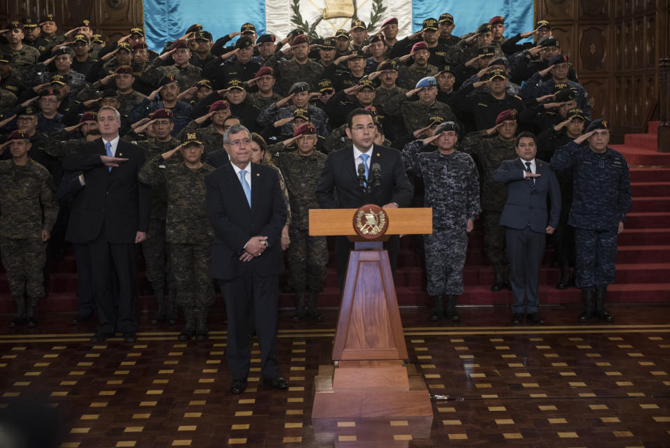 Guatemalan President Jimmy Morales speaks to the nation flanked by military officers, in Guatemala City, Friday, Aug. 31, 2018. Morales said he is not renewing the mandate of a U.N.-sponsored commission that has pressed a number of high-profile corruption probes in the country, including against him. (AP Photo/ Oliver de Ros)