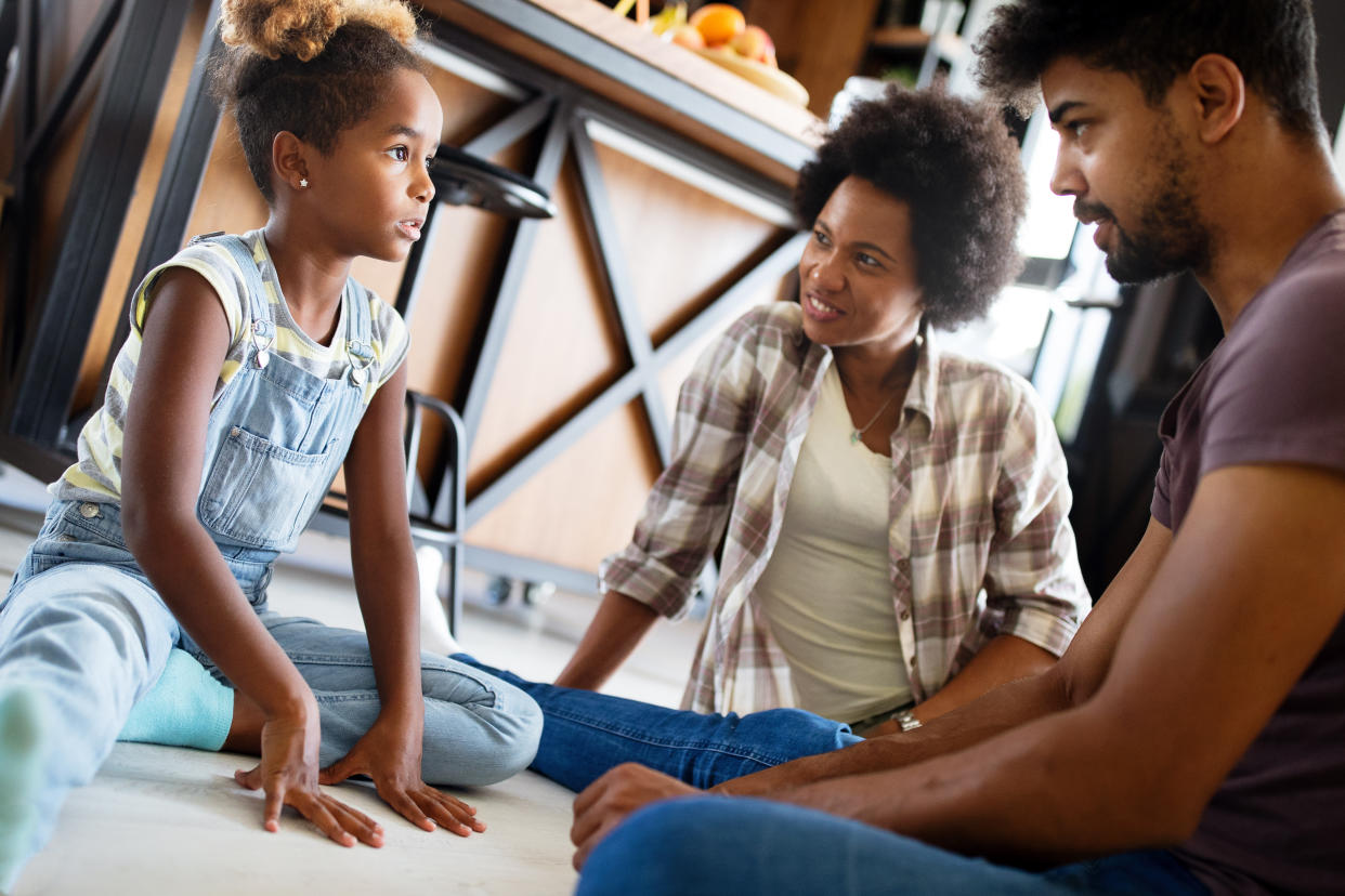 A young girl has a conversation with two people who appear to be her parents.