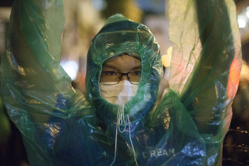 Pro-democracy protester wears a rain cover standing with others outside Police headquarters during a rally in Bangkok, Thailand, Wednesday, Nov. 18, 2020. Police in Thailand's capital braced for possible trouble Wednesday, a day after a protest outside Parliament by pro-democracy demonstrators was marred by violence that left dozens of people injured. (AP Photo/Wason Wanichakorn)