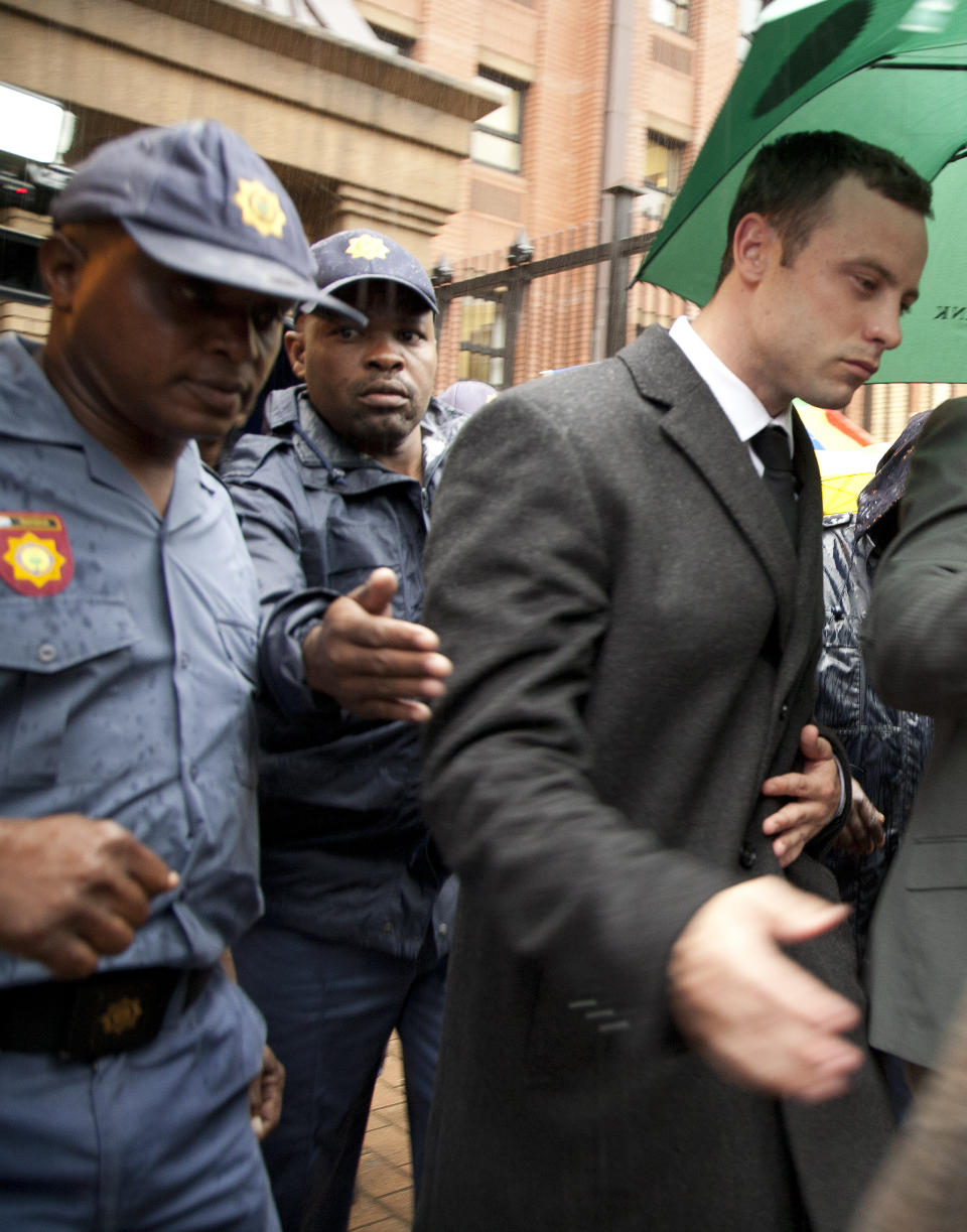 Oscar Pistorius, right, is escorted by police officers as he leaves the high court in Pretoria, South Africa, Monday, March 10, 2014. Pistorius is charged with murder for the shooting death of his girlfriend, Reeva Steenkamp, on Valentines Day in 2013. (AP Photo/Themba Hadebe)