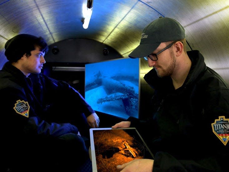 Two men are looking at screens inside the Titan.