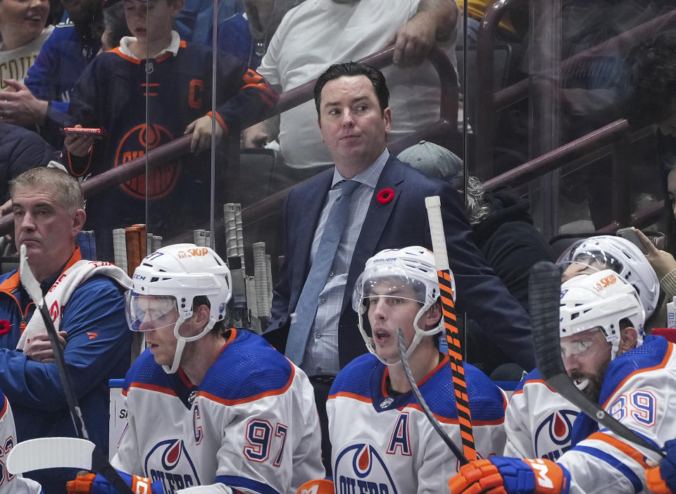 Edmonton Oilers head coach Jay Woodcroft, center, stands on the team bench during the third period of an NHL hockey game against the Vancouver Canucks, in Vancouver, British Columbia, on Nov. 6, 2023. Woodcroft is out as coach of the Oilers after the supposed Stanley Cup contenders lost 10 of their first 13 games this season. Woodcroft was fired Sunday, Nov. 12, 2023. Kris Knoblauch, Connor McDavid's junior hockey coach, was named Woodcroft's replacement, and Hall of Famer Paul Coffey joins his staff as an assistant. (Darryl Dyck/The Canadian Press via AP)