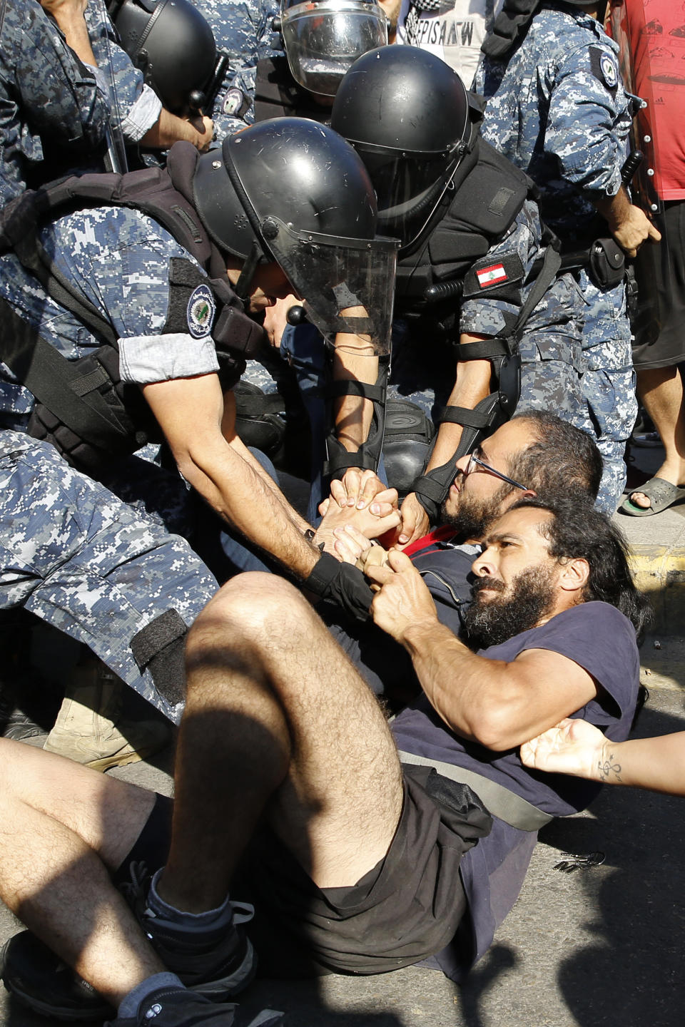 Anti-government protesters lie on a road holding each other as riot police try to remove them and open the road, in Beirut, Lebanon, Thursday, Oct. 31, 2019. Army units and riot police took down barriers and tents set up in the middle of highways and major intersections Thursday. (AP Photo/Bilal Hussein)