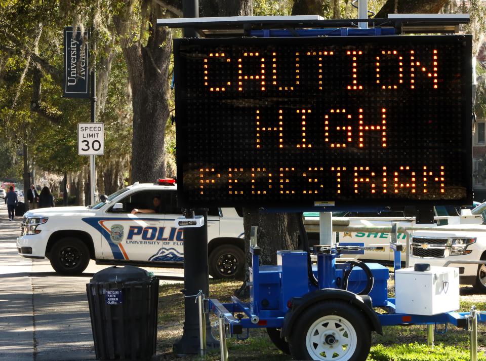 A University of Florida police officer watches traffic pass a recently placed street warning sign that reads "Caution High Pedestrian Traffic Area Ahead," during the start of operation Gator Steps by the City of Gainesville, the Gainesville Police Department, UF and the UF Police Department off West University Ave. in Gainesville Fla., Jan. 29, 2021. The operation, which will last about 30 days to start off, involves law enforcement using aggressive tactics to catch motorists that are not yielding right of way to pedestrians. The operation is in response to the recent deaths of two University of Florida students in crashes on University Avenue near campus. [Brad McClenny/The Gainesville Sun]