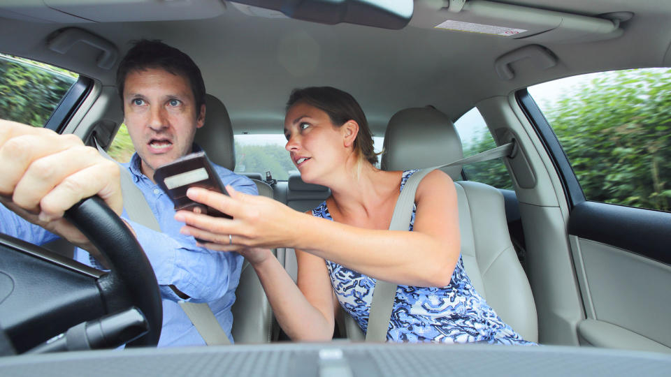 Couple in car looking at a phone for directions