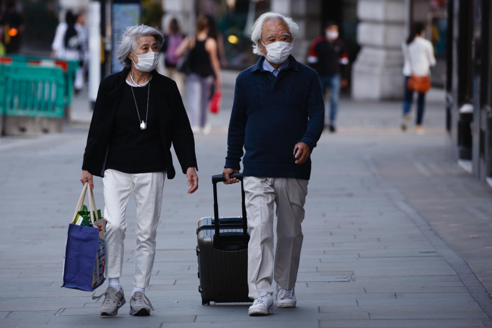 An elderly couple wearing face masks walk along Regent Street in London, England, on September 22, 2020. British Prime Minister Boris Johnson this afternoon announced a raft of new coronavirus restrictions to apply across England, possibly to last the next six months, including requiring pubs and restaurants to close at 10pm and for retail staff to all wear face masks. A return to home working where possible is also being encouraged. The new measures come amid fears of a 'second wave' of covid-19 deaths prompted by rising numbers of people testing positive in recent weeks. (Photo by David Cliff/NurPhoto via Getty Images)