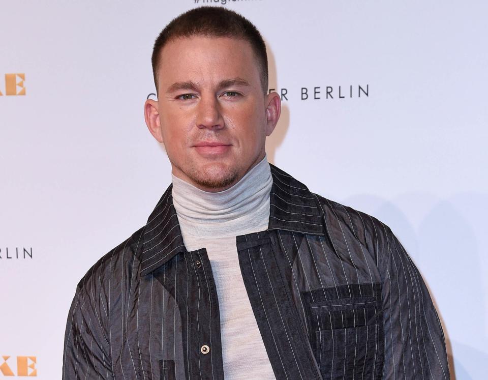 Channing wears a grey turtleneck shirt and pinstripe jacket