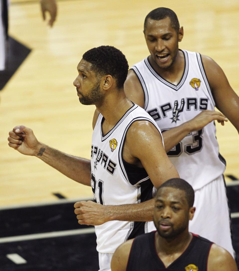 San Antonio Spurs' Tim Duncan (L) celebrates with Boris Diaw of France (R) as Miami Heat's Dwyane Wade walks past during the third quarter in Game 5 of their NBA Finals basketball series in San Antonio, Texas, June 15, 2014. REUTERS/Mike Stone (UNITED STATES - Tags: SPORT BASKETBALL)